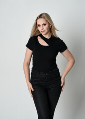 Canvas Print - Close up portrait of beautiful blonde woman wearing modern black shirt and leather pants. Confident  standing pose with hand gestures, isolated on white studio background.