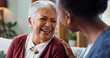 © peopleimages.com - Happy face, nurse and elderly patient in nursing home for healthcare and volunteer with charity on sofa. African caregiver, laughing and embrace a senior lady with trust and medical support on couch