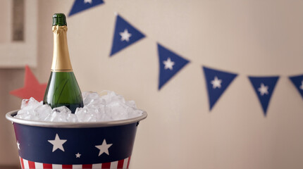 Champagne bottle in ice bucket with paper garland in background. Celebration of usa independence day, 4th of July. Red, blue, white American national colours