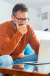 © simona - One thoughtful adult man in front of an open laptop thinking touching his face. Using computer and problems. Security password lost issue. Remote working. Looking for a solution concept people online