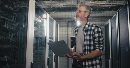 Man Holding Laptop in Server Room