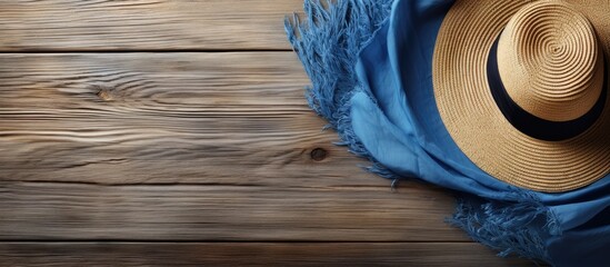 Wall Mural - A vintage themed copy space image featuring a wooden background with a straw hat adorned with a blue scarf