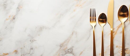 Poster - Design concept with clean golden metal cutlery on a light marble background in a top view copy space image