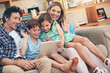 © peopleimages.com - Happy family, video call and wave with tablet on sofa for communication or conversation together at home. Mom, dad and young children with smile on technology for virtual discussion in living room