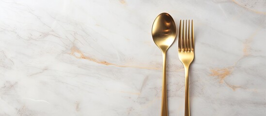 Poster - Design concept with clean golden metal cutlery on a light marble background in a top view copy space image
