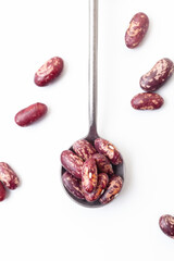 Wall Mural - Dry grains of red and white beans in iron spoon on white background