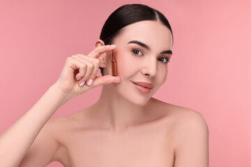 Sticker - Beautiful young woman holding skincare ampoule on pink background