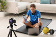 © New Africa - Smiling sports blogger recording fitness lesson with camera at home
