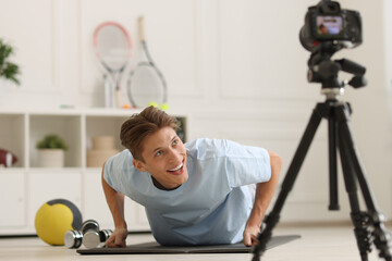 Poster - Smiling sports blogger doing push-ups while recording fitness lesson with camera at home