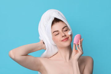 Canvas Print - Young woman washing face with brush and cleansing foam on light blue background