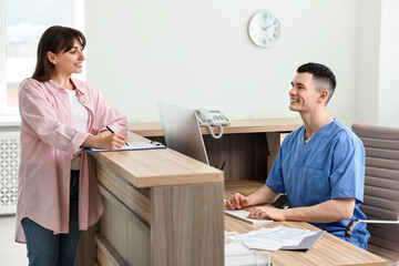 Sticker - Smiling medical assistant working with patient at hospital reception