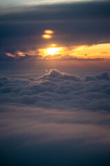 Wall Mural - View from a plane's window of the sun setting in cloudy skies