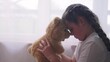 © maxximmm - depressed girl child sitting by the window with her favorite toy teddy bear upset. problem of domestic violence in the family concept. depressed girl is sad sunlight and bored at window with bear