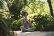 © insta_photos - Happy mindful young Hispanic woman meditating doing yoga breathing exercises feeling peace of mind, mental balance sitting in lotus pose hands in namaste in green nature park outdoors.