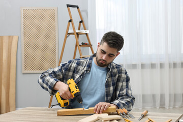 Sticker - Young handyman working with electric drill at table in workshop