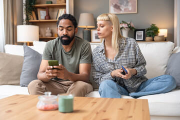 Young couple at home have a problem and argue due to jealousy caused by chatting and flirting via social media networks on smart phones, relationship difficulties problems and distrust