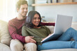 © peopleimages.com - Couple, watch and laptop for movies, bonding and entertainment with subscription on sofa and lounge. People, man and woman with computer, enjoy and internet for video, home and cozy for date on couch