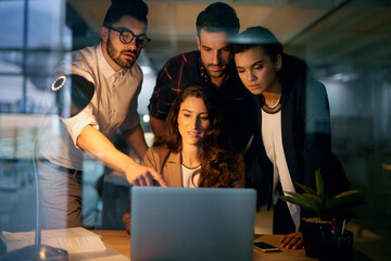 Poster - Laptop, group and pointing in night, smile and overtime for project of web designer, men and women. Startup, work and employees in collaboration, happy and online together or teamwork in office