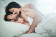 © peopleimages.com - Romance, morning and couple in bed with kiss, love and happy bonding in apartment. Relationship, man and woman relax in bedroom with intimate embrace, passion and wake up with care on weekend in home