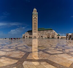 Wall Mural - view of the exterior and the minaret of the Hassan II Mosque in casablanca with reflections on the wet marble in the foreground