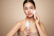 © Oleg Gekman - Young girl holds cotton pad while cleansing face with cosmetic milk. Skin care removal of makeup cleansing. Basic facial skin care