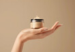 © ink drop - Womans hand with a jar of anti ageing cosmetics moisturiser cream against a beige tone background