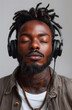 © Анна Терелюк - Portrait of young man with dreadlocks listening to music with headphones on gray background