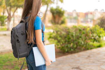 Poster - Teenager girl at outdoors holding a notebook