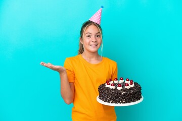 Wall Mural - Little caucasian girl holding birthday cake isolated on blue background with shocked facial expression