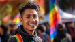© Sachin - Young Latin American man smiles with pride at an LGBTQ+ parade, celebrating acceptance and community under a rainbow flag on a sunny day