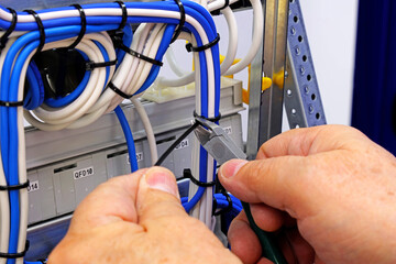 Poster - Cutting the cable tie on the insulated mounting wire in the electrical panel.