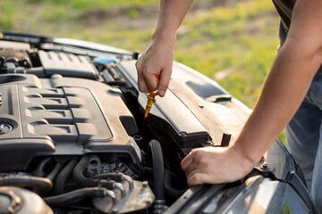 Man hands checking oil level in engine before trip or journey by automobile, closeup. Car check condition concept