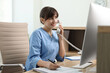 © New Africa - Smiling medical assistant talking by phone in office