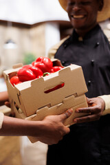 Canvas Print - A smiling black man in a modern store offers fresh local produce, reusable containers, and bulk options for an eco-conscious lifestyle. Close-up shot of vendor receiving crates of products.