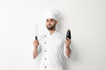 Canvas Print - Professional chef holding knife and eggplant on white background