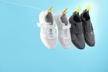 Wall Mural - Different stylish sneakers drying on washing line against light blue background