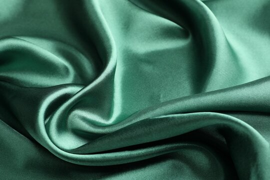 Crumpled green silk fabric as background, closeup