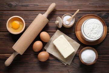 Wall Mural - Making shortcrust pastry. Rolling pin and different ingredients for dough on wooden table, flat lay