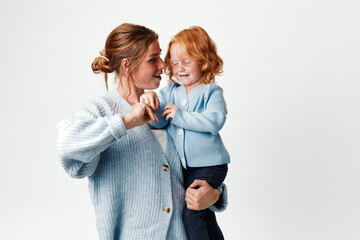 Wall Mural - Mother and daughter embracing in front of white background, love and affection concept for family photoshoot