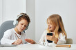 © SHOTPRIME STUDIO - Happy Caucasian siblings sitting at the study table in their cozy living room, engrossed in online elearning The brother and sister are using their laptops, headphones on, typing and playing
