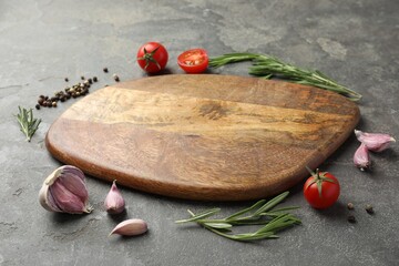 Canvas Print - Cutting board, rosemary, garlic, pepper and tomatoes on black table. Space for text