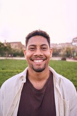 Vertical portrait of an Handsome happy African American bearded man. Cheerful young man outdoors and smiling at camera. Positive emotion concept of male person. Generation z guy look carefree natural