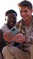 Wall Mural - Vertical multiracial group of teenagers taking a selfie looking front camera laughing and having fun piggybacking together outdoor. Young students enjoying their free time with friends in street city