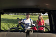 © 24K-Production - Inside car view of a young couple, the electric mountain bikers, a man unloading EMTB from the hitch rack on the rear of the vehicle.