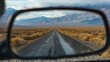 © buraratn - Close-up of a rearview mirror reflecting a long, open road with mountains in the distance