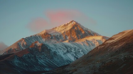 Wall Mural - A mountain range bathed in the golden light of sunrise, with a clear sky gradually transitioning to blue.