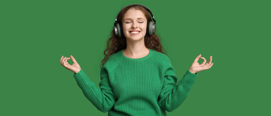 Wall Mural - Portrait of relaxed young woman meditating while listening to music on green background