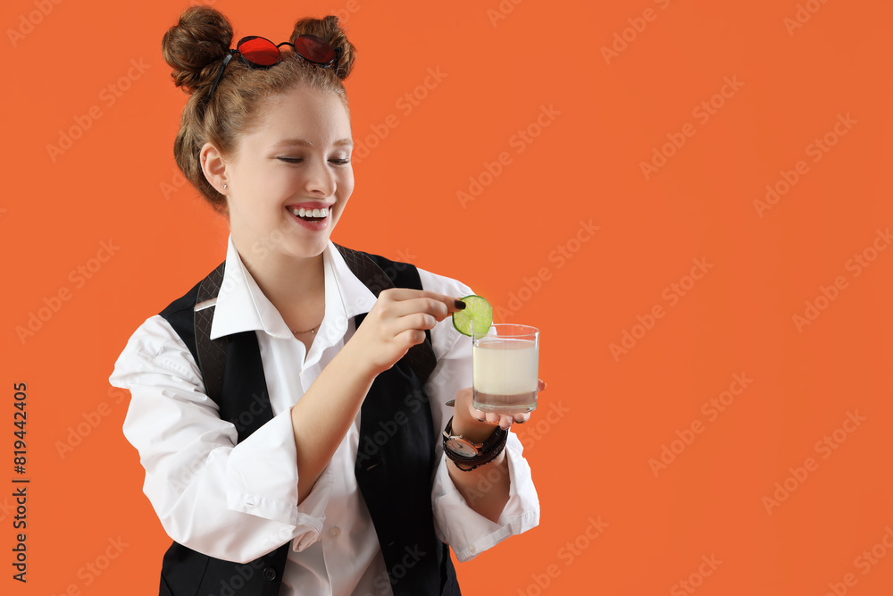 Female bartender with cocktail on orange background