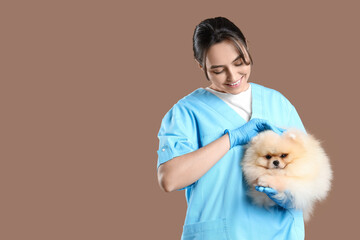 Sticker - Female veterinarian with cute Pomeranian dog on beige background