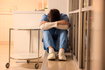 Sticker - Stressed male nurse sitting on windowsill at hospital in evening